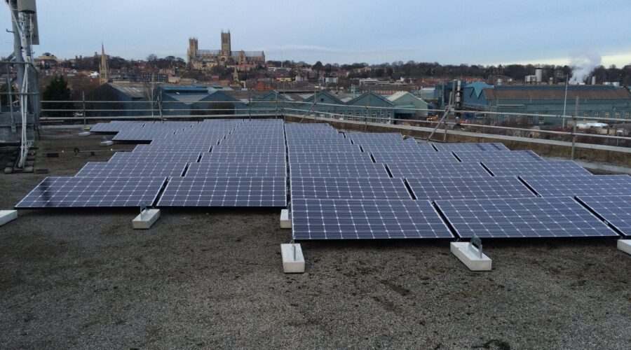 An array of solar panels on a Lincolnshire buisness with the Lincoln Cathedral visible in the background.